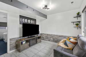 Living room with wainscoting, tile walls, and a textured ceiling