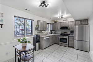 Kitchen featuring stainless steel appliances, light countertops, tasteful backsplash, and hanging lights