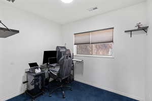 Home office featuring dark carpet and baseboards