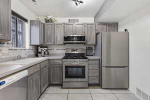 Kitchen featuring stainless steel appliances, light countertops, light marble finish floors, and decorative backsplash