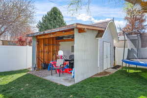 View of shed featuring a trampoline and a fenced backyard