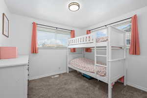 Bedroom featuring dark carpet and baseboards