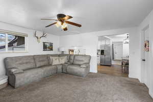 Living area featuring a ceiling fan and dark carpet