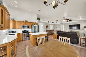 Dining room featuring light wood-style floors, suspended lighting, vaulted ceiling, and ceiling fan