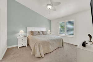 Bedroom with vaulted ceiling, light colored carpet, and a ceiling fan