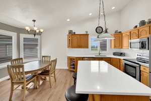 Kitchen with light wood-type flooring, lofted ceiling, backsplash, stainless steel appliances, and a kitchen bar