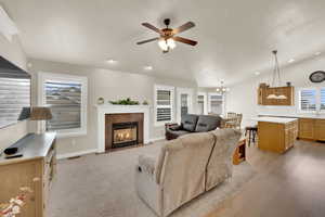 Living room with ceiling fan, lofted ceiling, a fireplace, and hanging lights