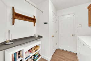Laundry room with light wood finished floors and washer and clothes dryer