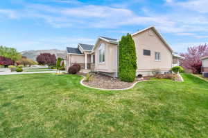 View of side of home featuring stucco siding, a lawn, a mountain view, and covered porch