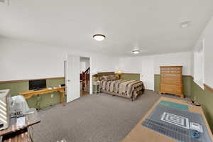 Bedroom with carpet flooring, an office area, and a textured ceiling