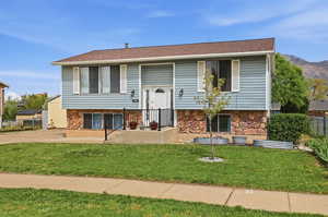 Split foyer home with stone siding and a shingled roof