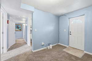 Foyer with light carpet and a textured ceiling