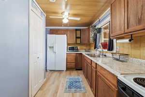 Kitchen with wood ceiling, white appliances, light countertops, and wood finish cabinets