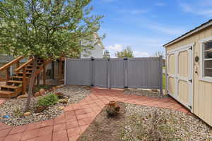 View of patio with a gate and a storage unit