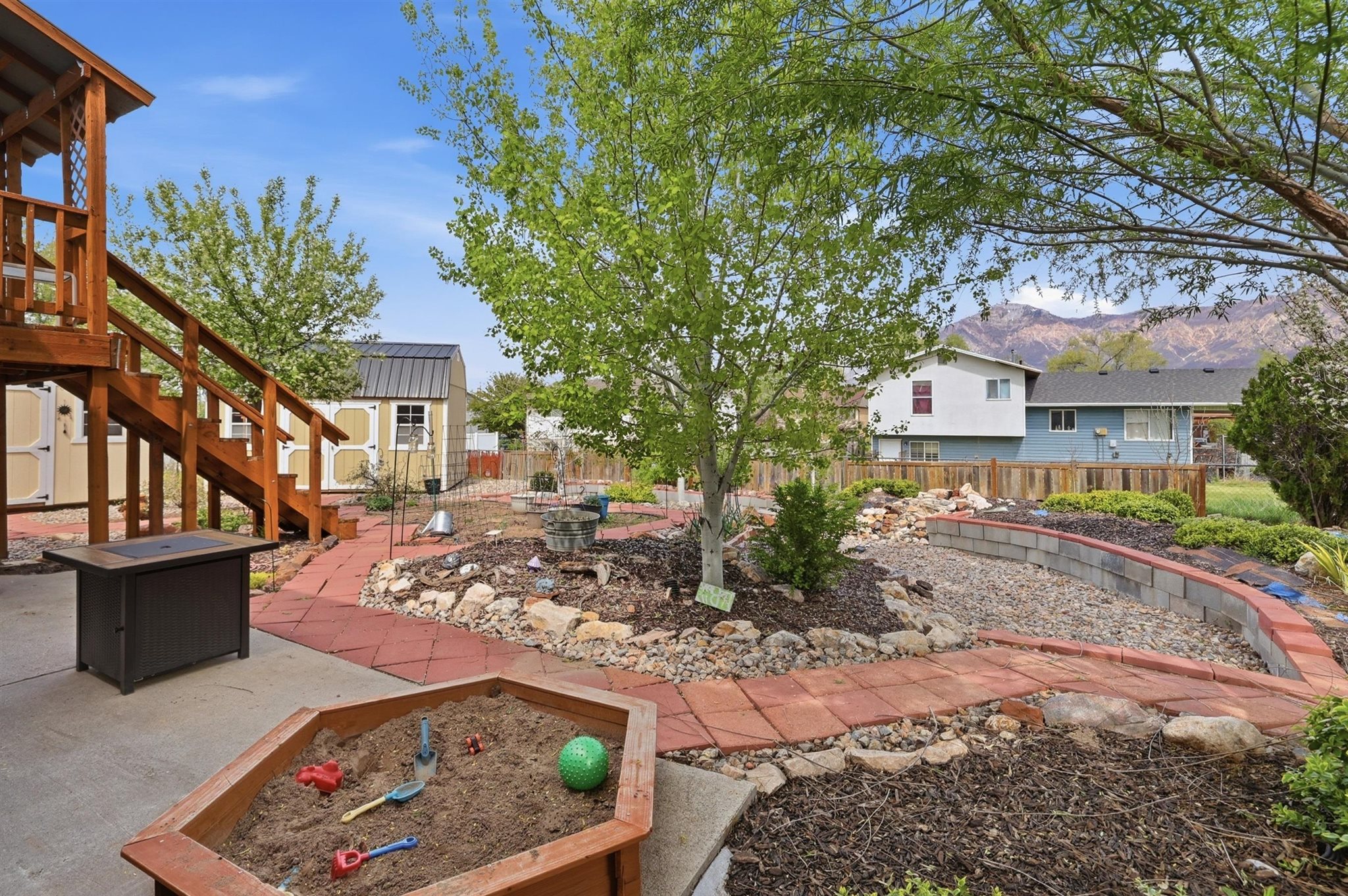 Fenced backyard with a patio area, a storage shed, a mountain view, and a garden