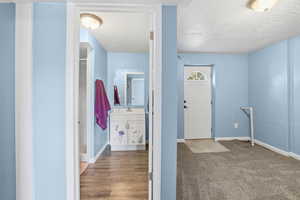 Corridor featuring a textured ceiling and light wood-style floors
