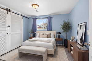 Bedroom featuring a barn door, a closet, and carpet floors