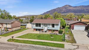 Raised ranch with driveway, a residential view, a front lawn, and a mountain view