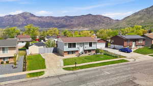 View of front of property with a residential view, brick siding, a mountain view, entry steps, and driveway