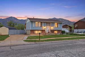 Raised ranch with a mountain view, concrete driveway, and stone siding