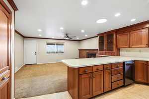 Kitchen featuring light countertops, glass insert cabinets, a peninsula, wood finish cabinetry, and a fireplace