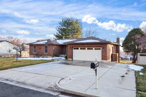 Single story home with brick siding, concrete driveway, a chimney, and a garage