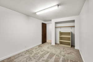 Unfurnished bedroom with light carpet, a closet, and a textured ceiling