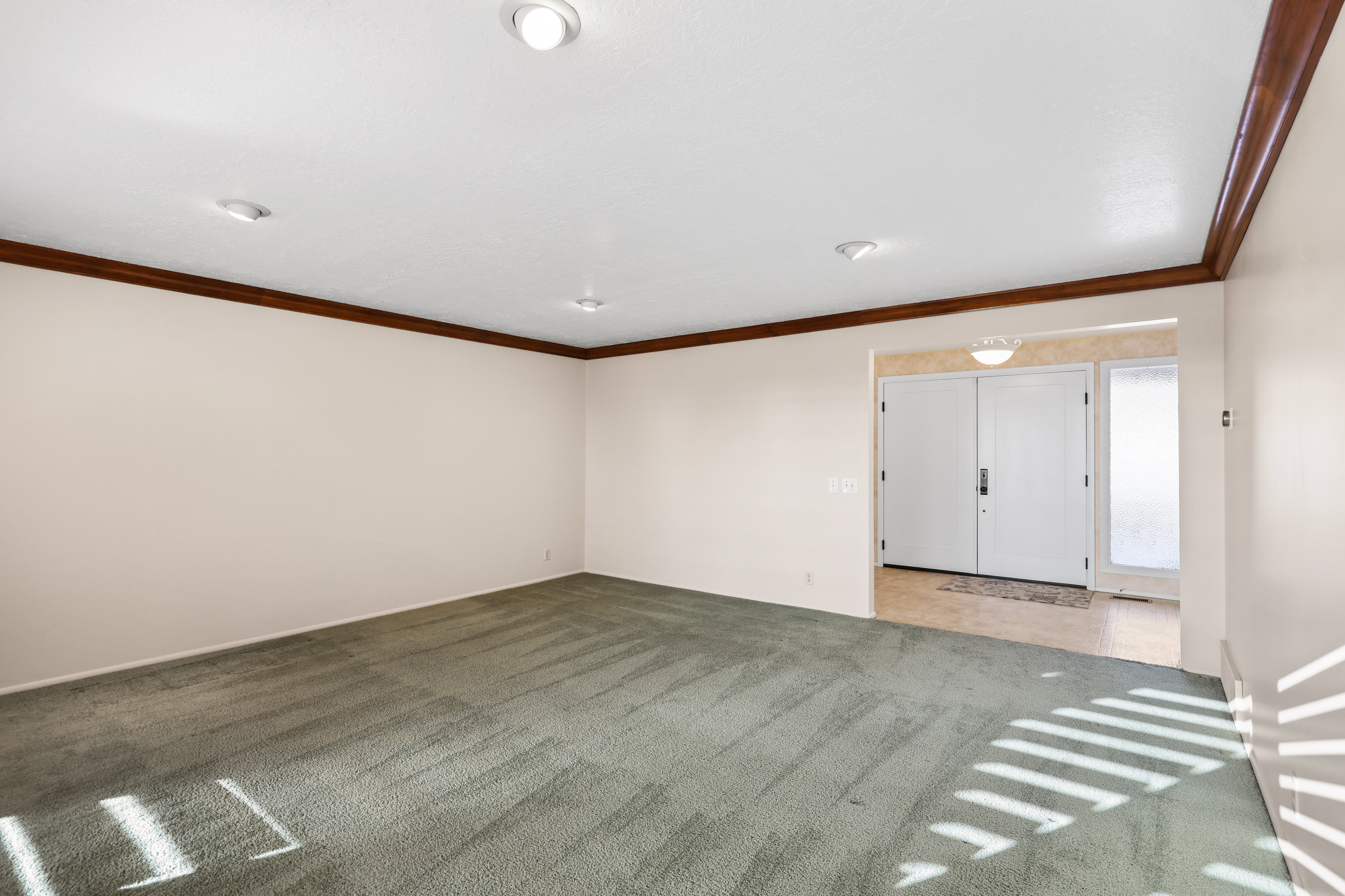 Empty room featuring ornamental molding and light colored carpet