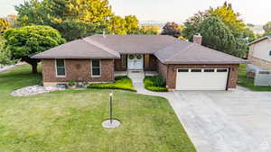 Ranch-style home featuring a garage, driveway, brick siding, and roof with shingles