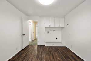 Laundry area with dark wood-style floors, hookup for a washing machine, a textured ceiling, electric dryer hookup, and cabinet space