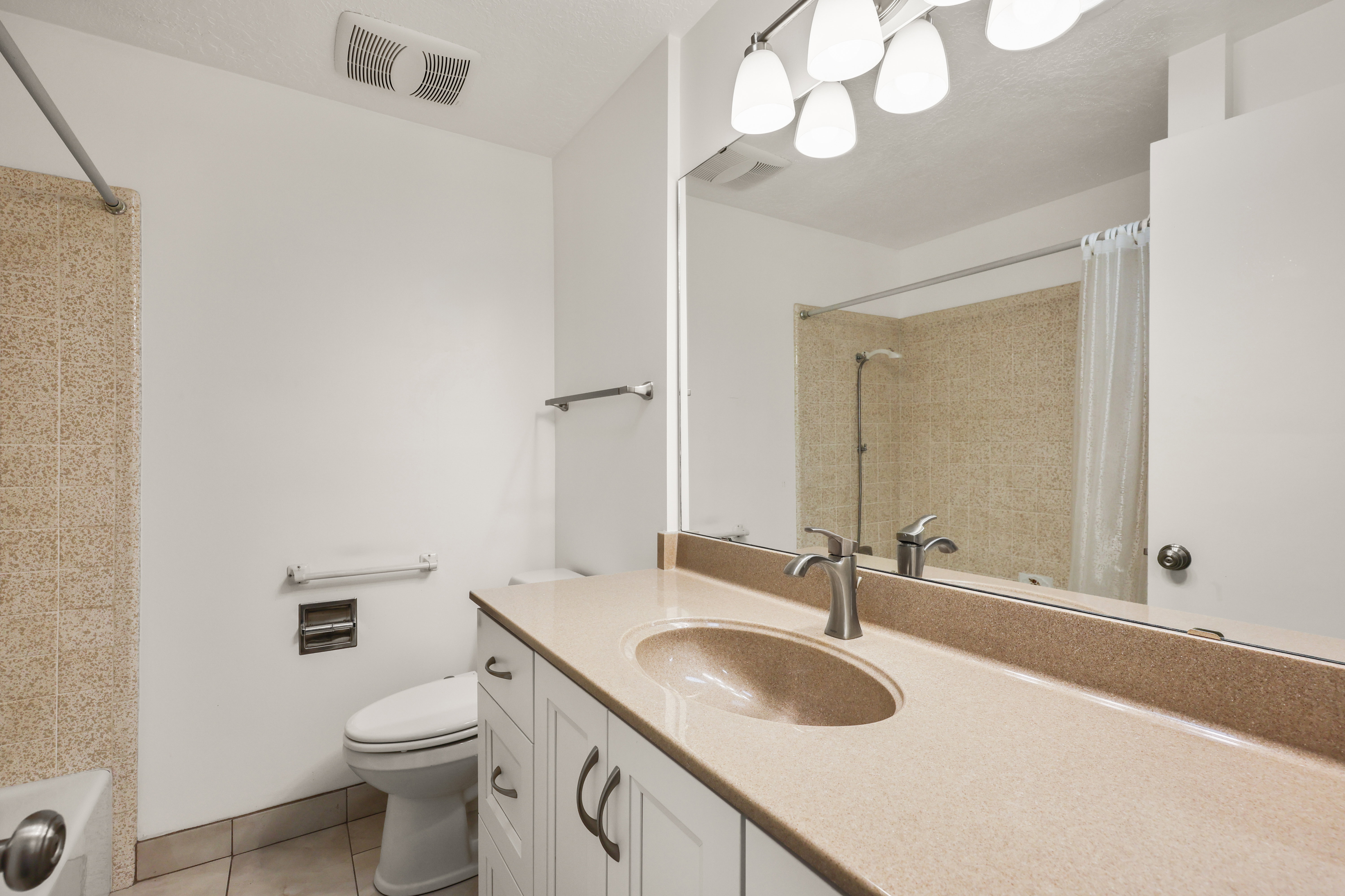 Full bath with vanity, light tile patterned floors, and shower / bath combo