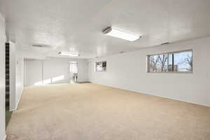 Unfurnished room featuring a textured ceiling and light colored carpet