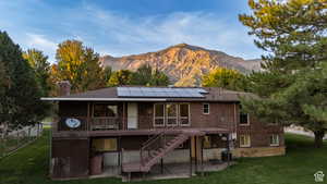 Back of property featuring a patio, a yard, a chimney, brick siding, and roof mounted solar panels