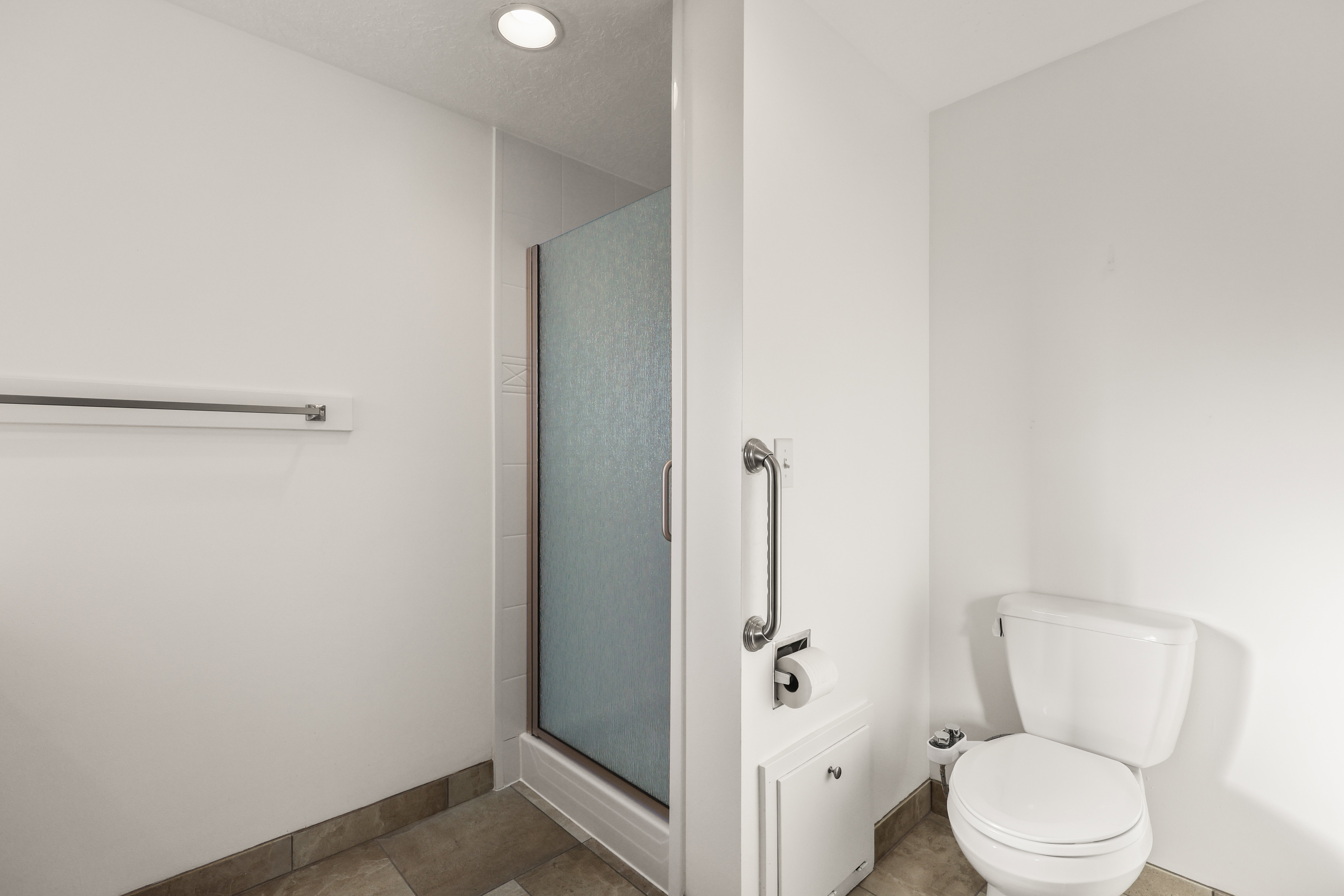 Bathroom featuring a shower stall and light tile patterned flooring