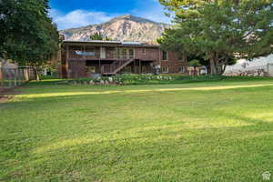 Rear view of property with a mountain view, a chimney, a yard, and brick siding