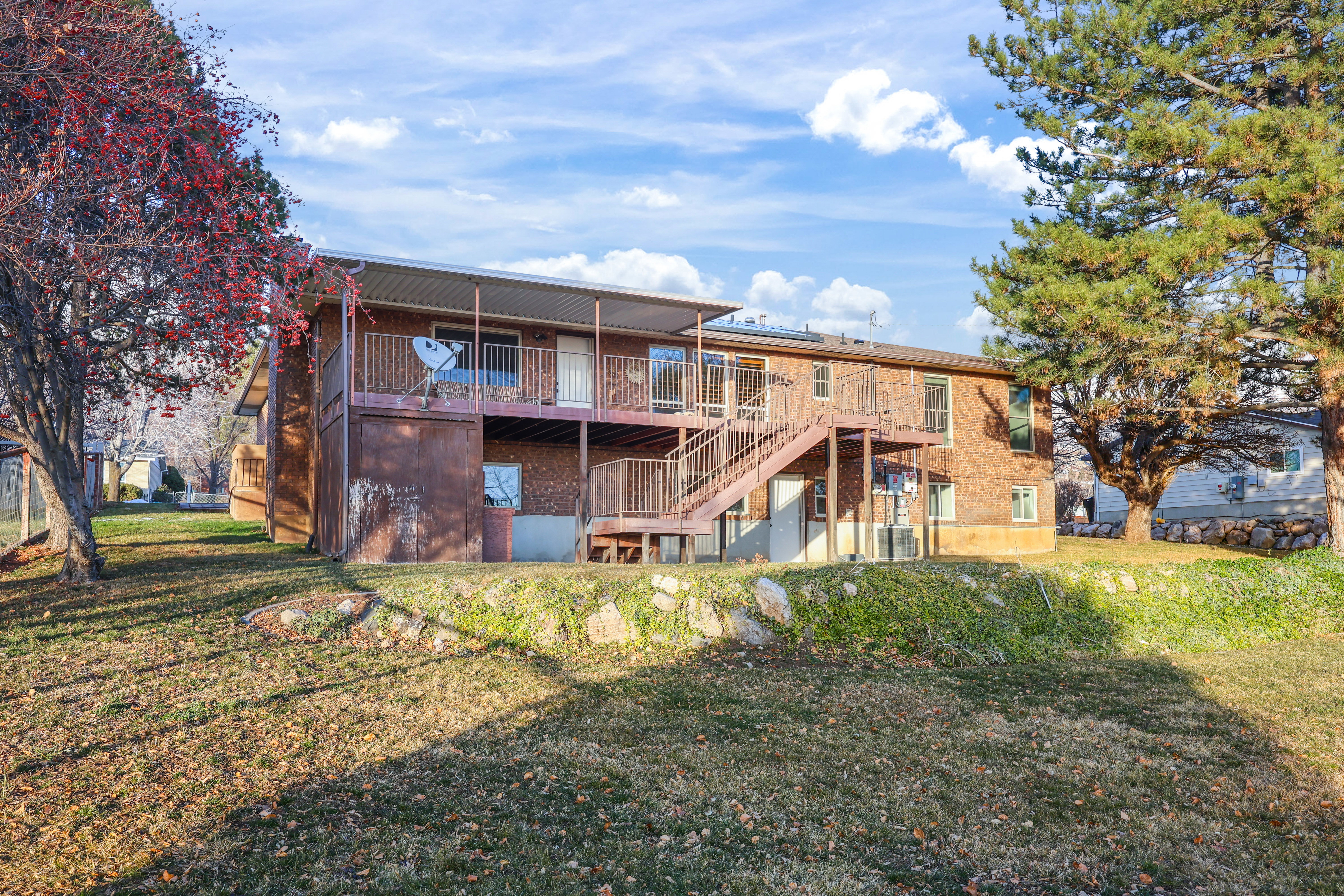 Back of house with a wooden deck, a yard, and brick siding