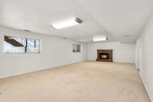 Below grade area with a brick fireplace, light carpet, and a textured ceiling