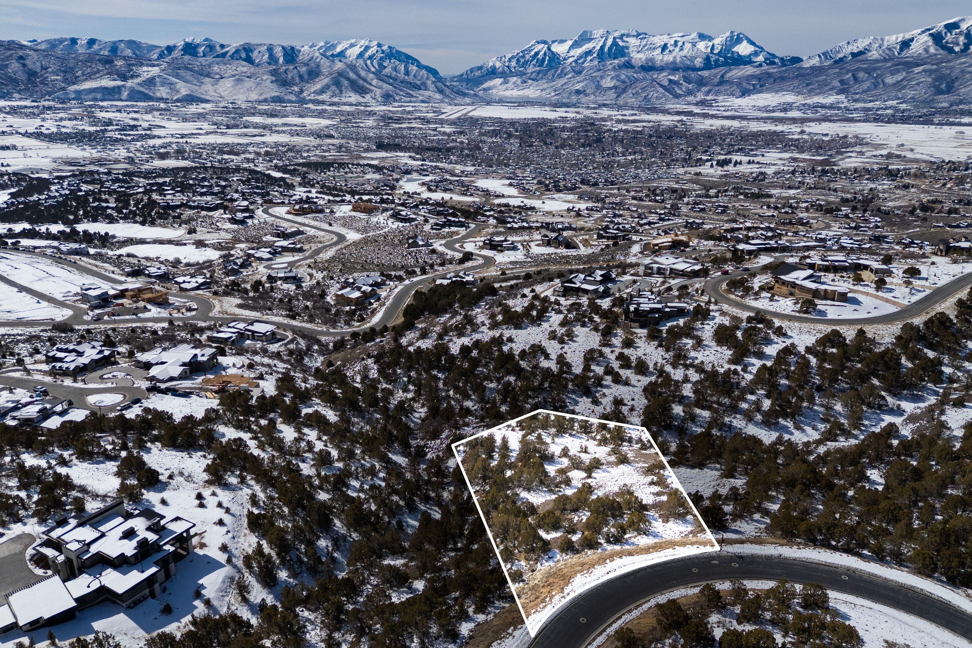 Snowy aerial view with a mountain view and property parcel outlined