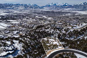 Snowy aerial view with a mountain view and property parcel outlined