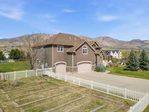 View of front of home with a mountain view, a garage, stone siding, and driveway