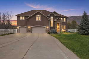 View of front facade featuring driveway, stone siding, and an attached garage