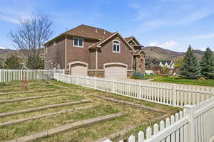 Back of house featuring an attached garage, a mountain view, stone siding, and concrete driveway