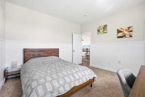Carpeted bedroom featuring wainscoting