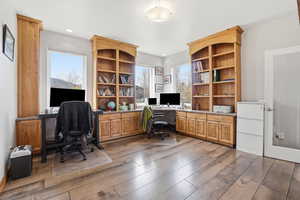 Home office with dark wood-style flooring and built in desk