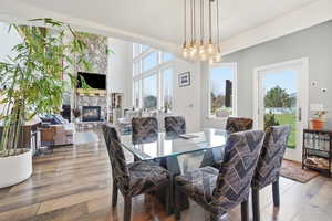 Dining area featuring a stone fireplace, wood-type flooring, and plenty of natural light