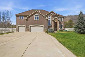 View of front of home featuring a garage, concrete driveway, and stone siding