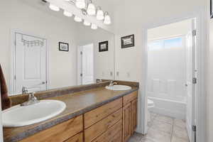 Bathroom featuring double vanity, light tile patterned flooring, and shower / bath combination