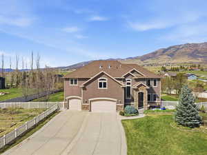 View of front of property featuring an attached garage, a mountain view, stone siding, driveway, and roof with shingles