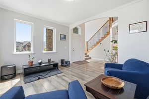 Living area with crown molding, light wood-style flooring, and arched walkways