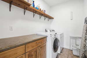 Laundry area with light tile patterned floors and washing machine and dryer